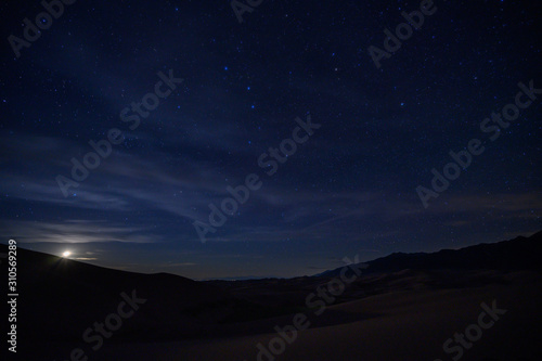 Moon Sets Below Sand Dunes and Star Field