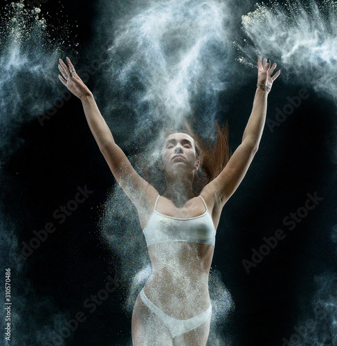 Pretty girl in cloud of white dust studio portrait