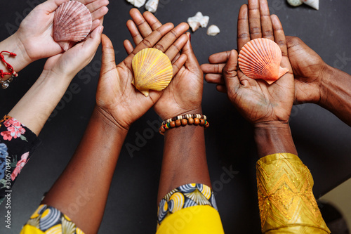 Hands of African people in traditional clothes holding seashells