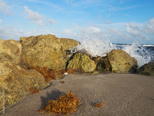 Wave crashes against rocks at the beach photo