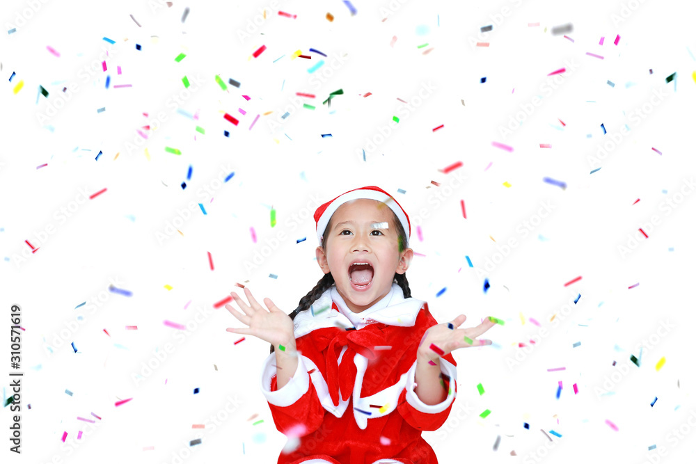 Happy child girl in Santa costume dress with colorful confetti on white background. Merry Christmas and Happy New Year Concept.