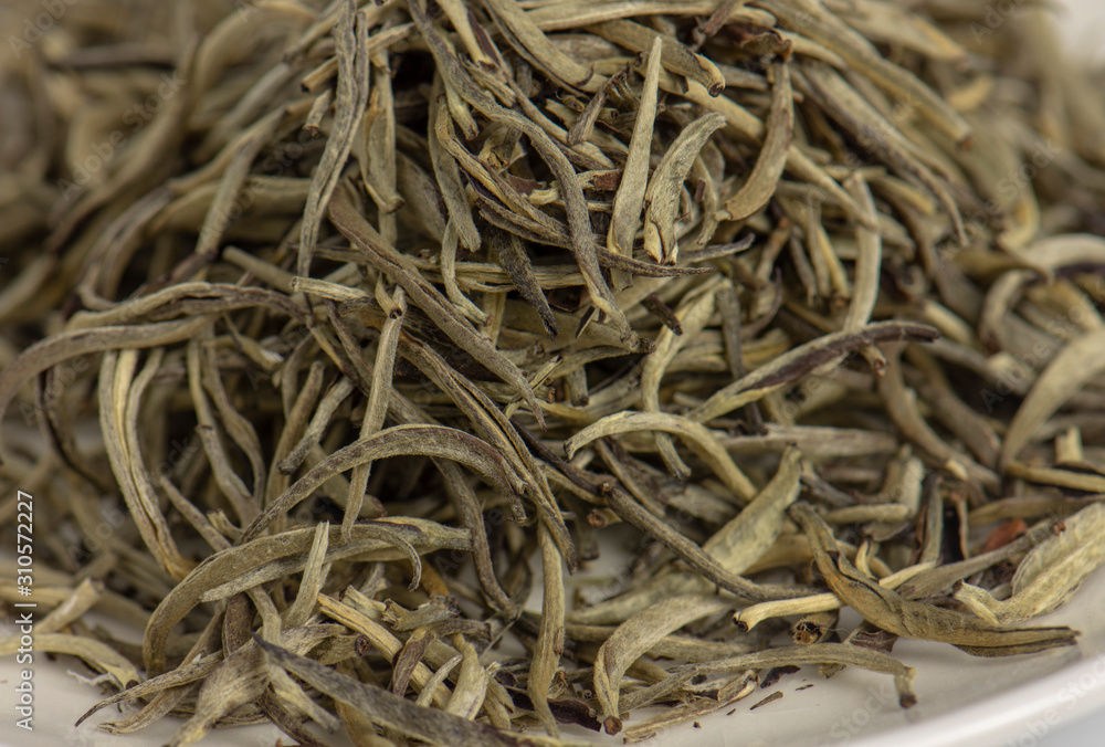 Close up of premium quality dried white tea leaves in small dish.