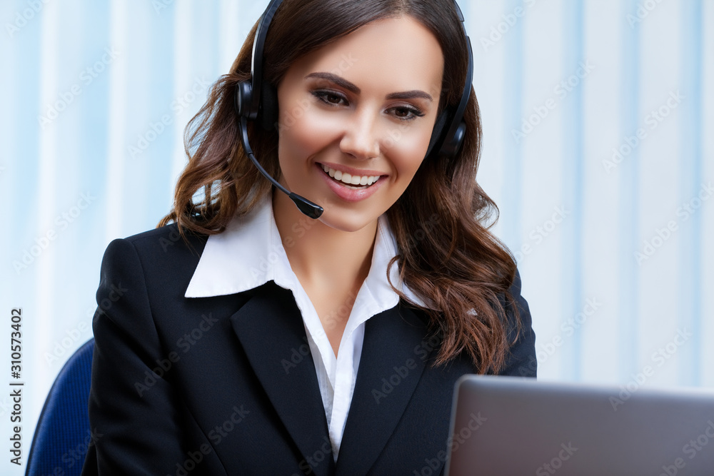 Portrait picture of customer support female phone operator or sales agent in headset and confident black suit, working with laptop at office workplace. Consulting and assistance service call center. Portrait picture of customer support female phone operator or sales agent in headset and confident black suit, working with laptop at office workplace. Consulting and assistance service call center.
