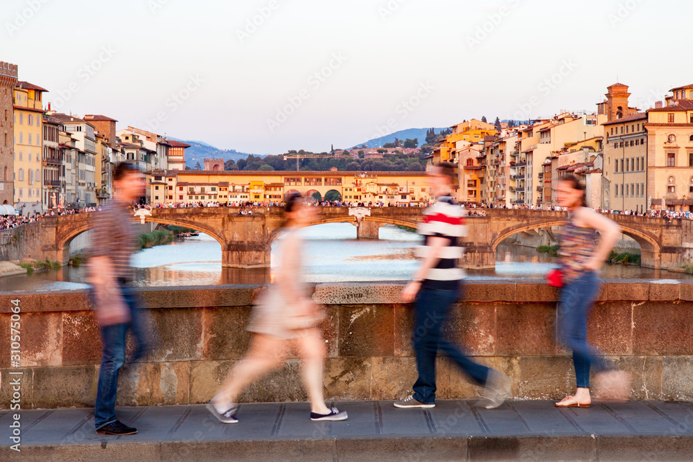 People Walking on Bridge Across Arno River in Front of Ponte Vecchio in Florence
