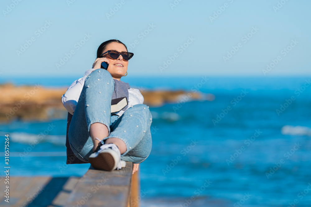 Woman laying down on a wooden railing talks on her phone