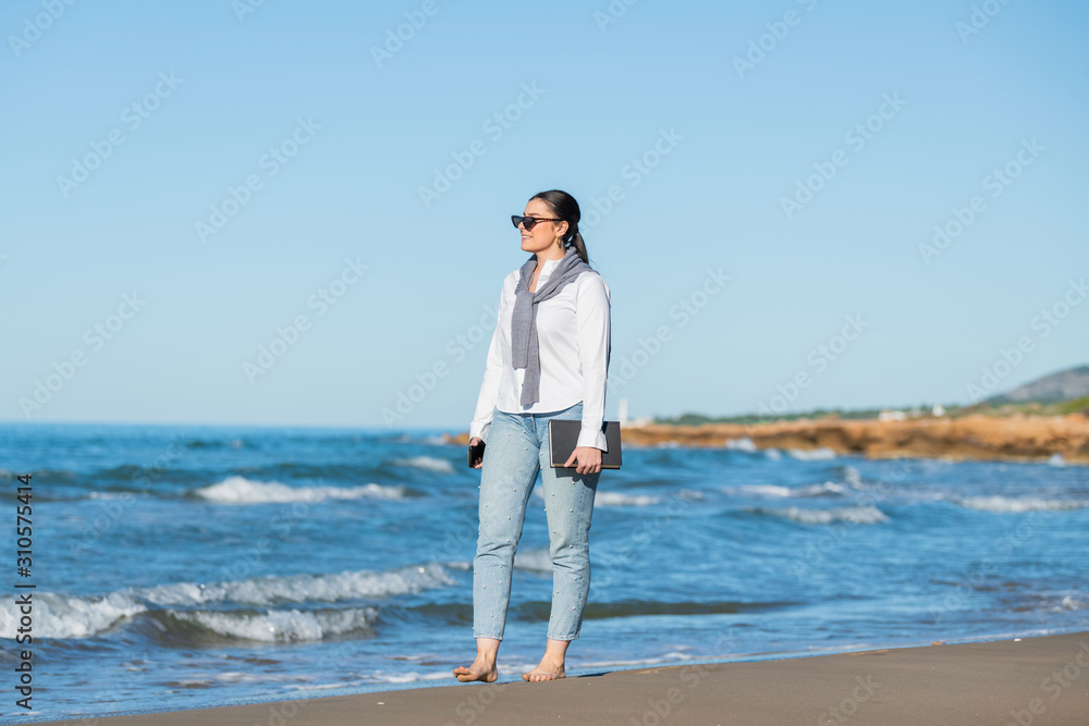 Woman looks ahead while walking along the beach
