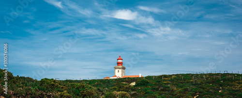 The lighthouse on the cliff in Cabo da Roca (Cape Roca) the westernmost extent of mainland Portugal, continental Europe and the Eurasian land mass. Bright sunny day panoramic landscape.