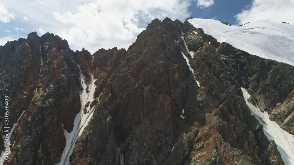 Drone fly upward to edge of ridge reveal mountain range cover with eternal snow Drone fly upward to edge of ridge reveal mountain range cover with eternal snow