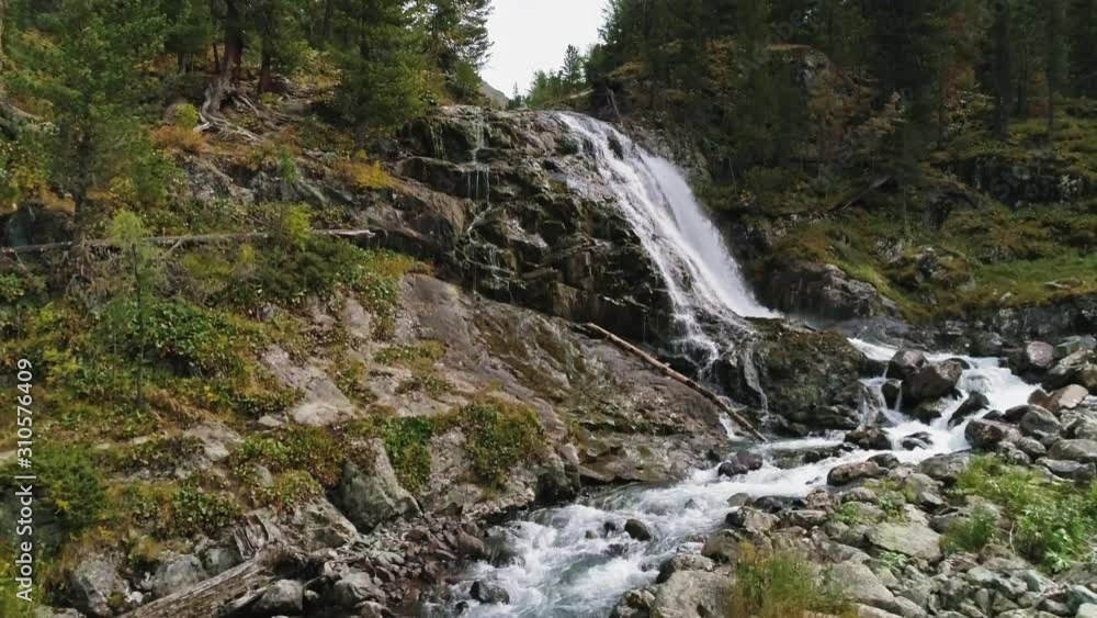 Drone fly above forest river upwards to wild waterfall stream among mossy stones Drone fly above forest river upwards to wild waterfall stream among mossy stones