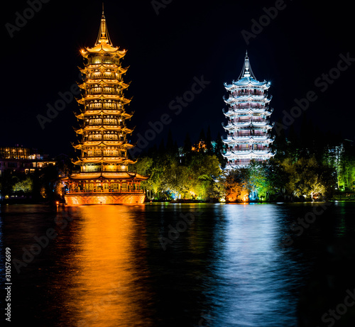 Bloom of two Chinese temple towers in Guilin. On Shanhu Lake’s shore, twin pagodas, the Sun and Moon, light up the sky at night. Long exposure, reflection in the water. photo