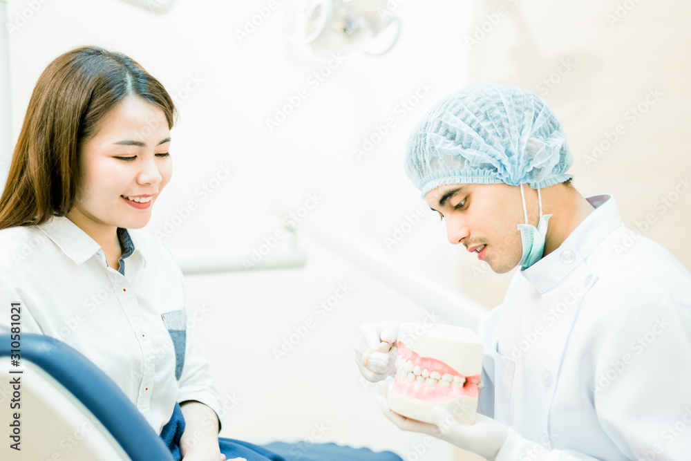 Dentist shows how to clean teeth. The doctor demonstrates brushing teeth with a toothbrush in a tooth model. Dentist shows how to clean teeth. The doctor demonstrates brushing teeth with a toothbrush in a tooth model.