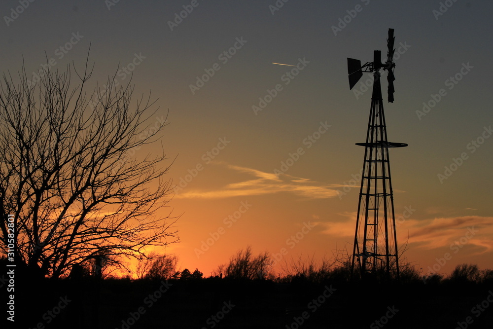 Kansas Sunset with a Windmill Silhouette, sky, and tree's out in the country.