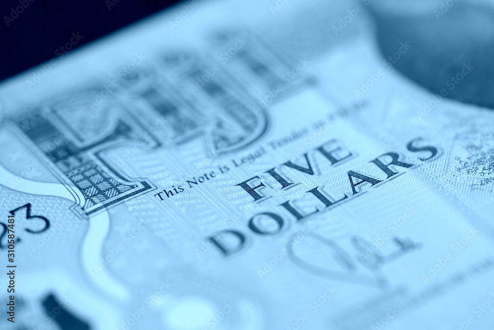 Five Fijian dollars banknote on a dark background close up. Money background blue color toned Five Fijian dollars banknote on a dark background close up. Money background blue color toned