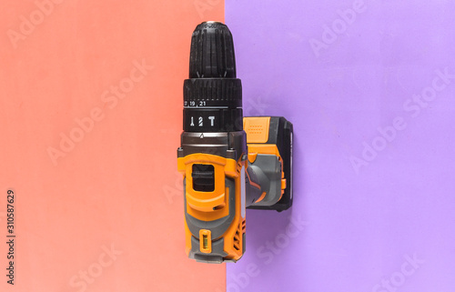 Isolated cordless drill electric power tool on two tones colorful background.