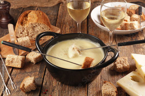 cheese fondue with wine and bread on wood background