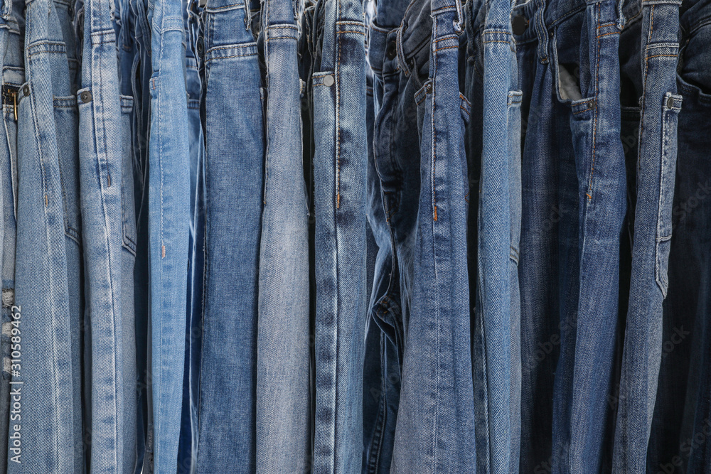 Different stylish jeans as background, closeup view