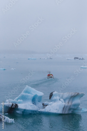 Man on a boat between bizarre ice floes of Iceberg lagoon jokulsarlon on the south of Iceland