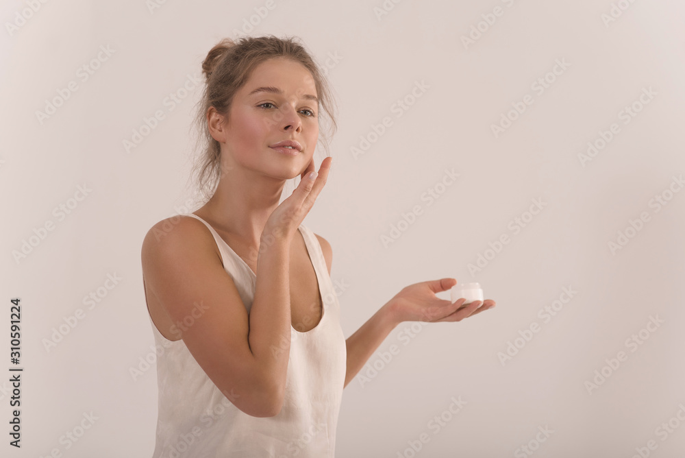 Portrait of a young attractive happy woman with a jar of cream in her hands. Portrait of a young attractive happy woman with a jar of cream in her hands.