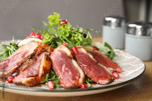 Delicious salad with roasted duck breast served on wooden table, closeup