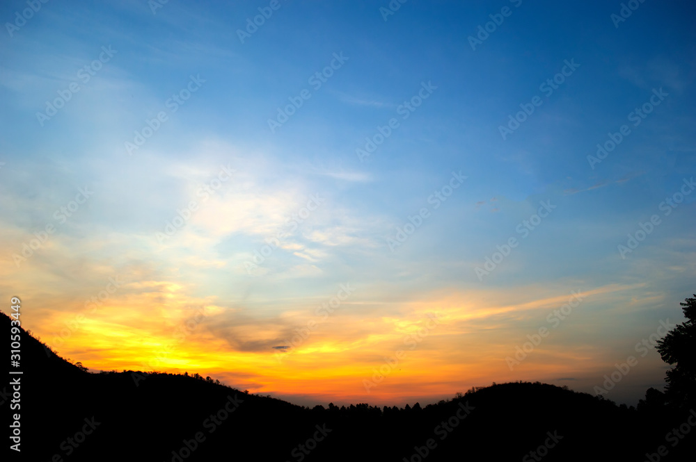 sunbeam from sunset behind  Silhouette Mountain with blue sky background