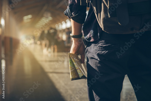 Tourist backpacker holding map standing at train station for travel. Travel concept