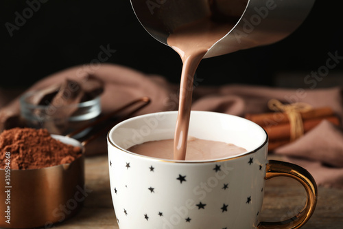 Canvastavla Pouring hot cocoa drink into cup on wooden table