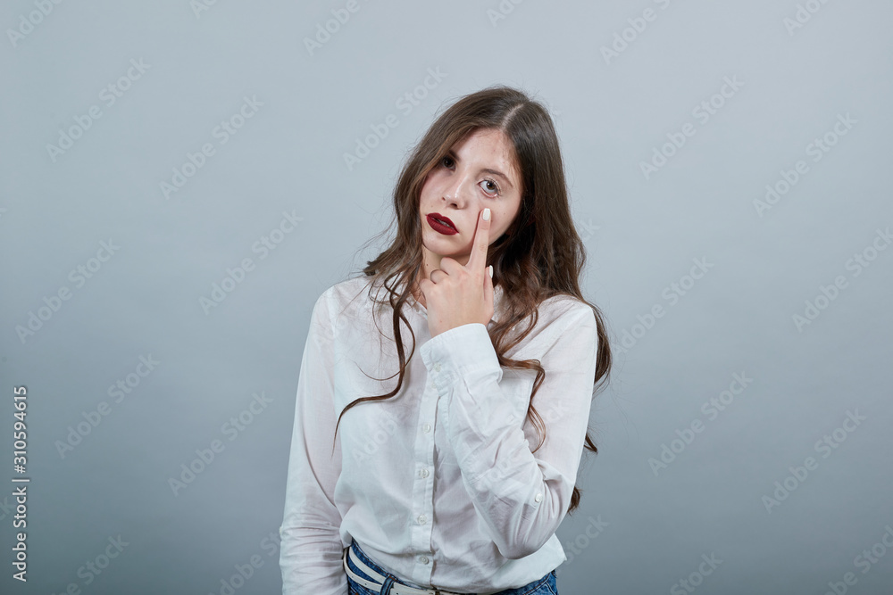 Disappointed young brunette woman over isolated gray background wearing casual white shirt, keeping fingers on cheek, crying. People lifestyle concepte. Disappointed young brunette woman over isolated gray background wearing casual white shirt, keeping fingers on cheek, crying. People lifestyle concepte.
