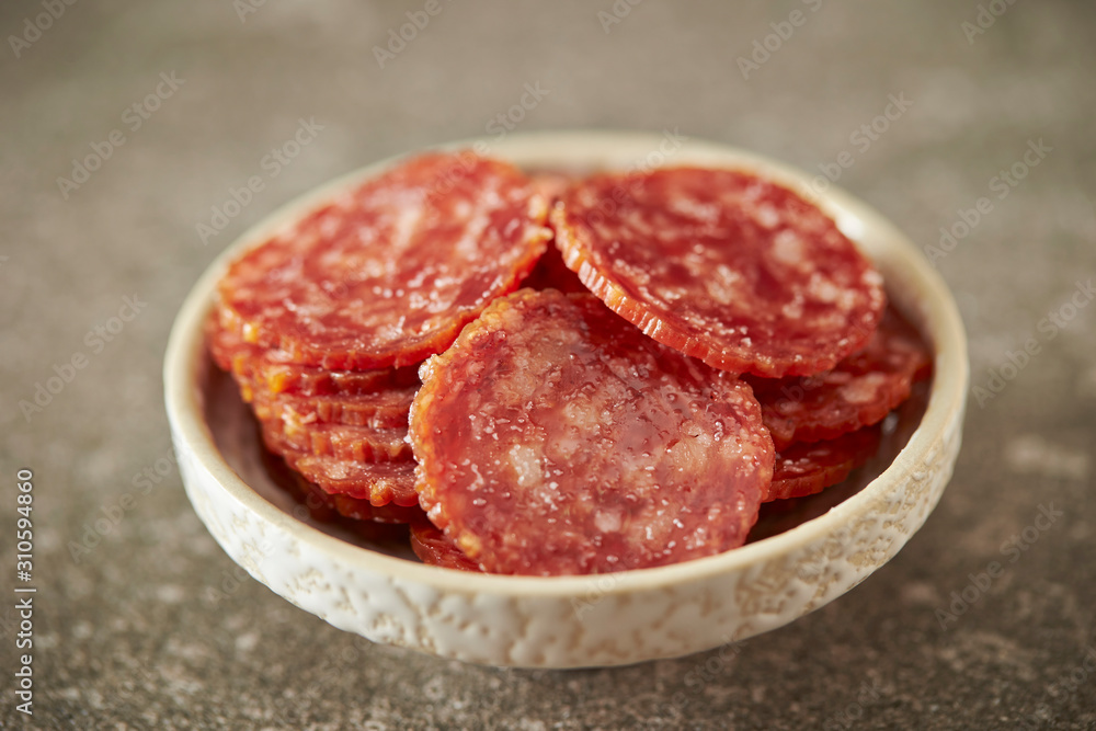 Thin sliced salami sausage on stone background Thin sliced salami sausage on stone background