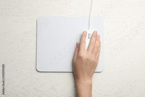 Woman using wired computer mouse on white wooden table, top view. Space for text