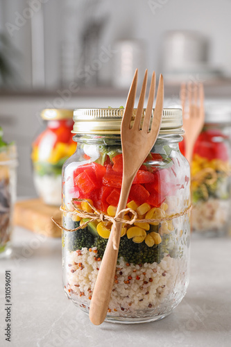 Glass jar with healthy meal on light grey marble table photo