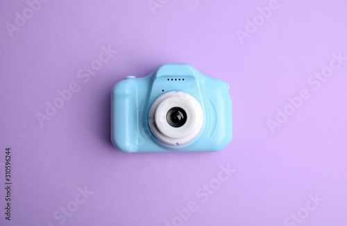 Light blue toy camera on violet background, top view. Future photographer