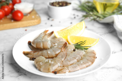 Fresh raw shrimps with lemon and rosemary on marble table