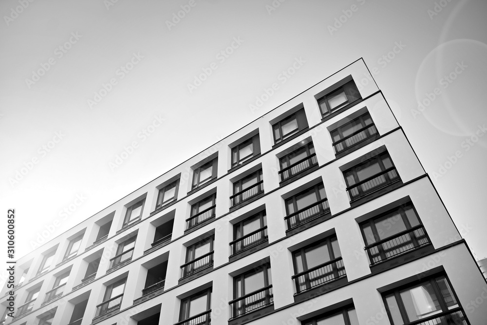 Sun rays light effects on urban buildings. Fragment of modern residential apartment with flat buildings exterior. Detail of new luxury house and home complex. Black and white.