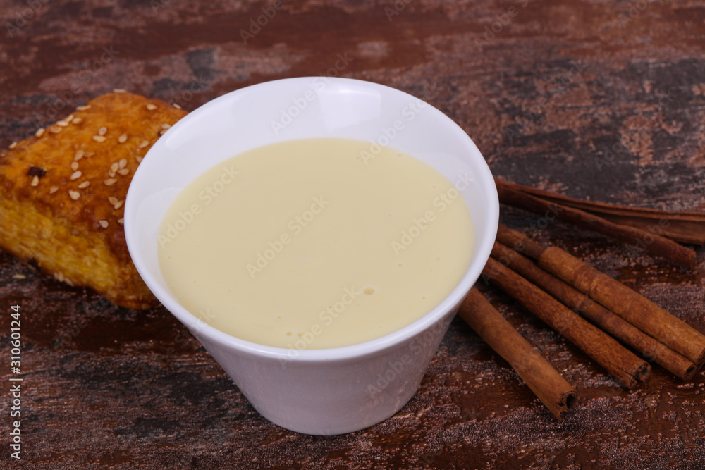 Condenced milk in the bowl with sinnamon and pastry Condenced milk in the bowl with sinnamon and pastry