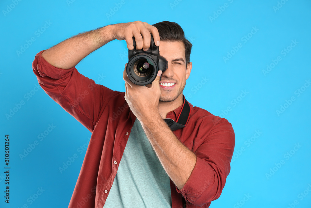 Fototapeta premium Professional photographer working on light blue background in studio