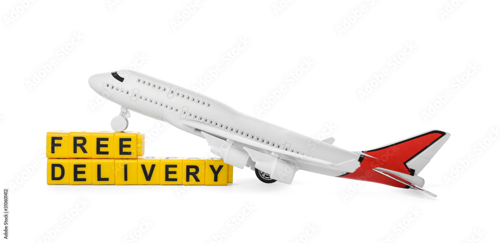 Toy plane and cubes with words FREE DELIVERY isolated on white. Logistics and wholesale concept Toy plane and cubes with words FREE DELIVERY isolated on white. Logistics and wholesale concept