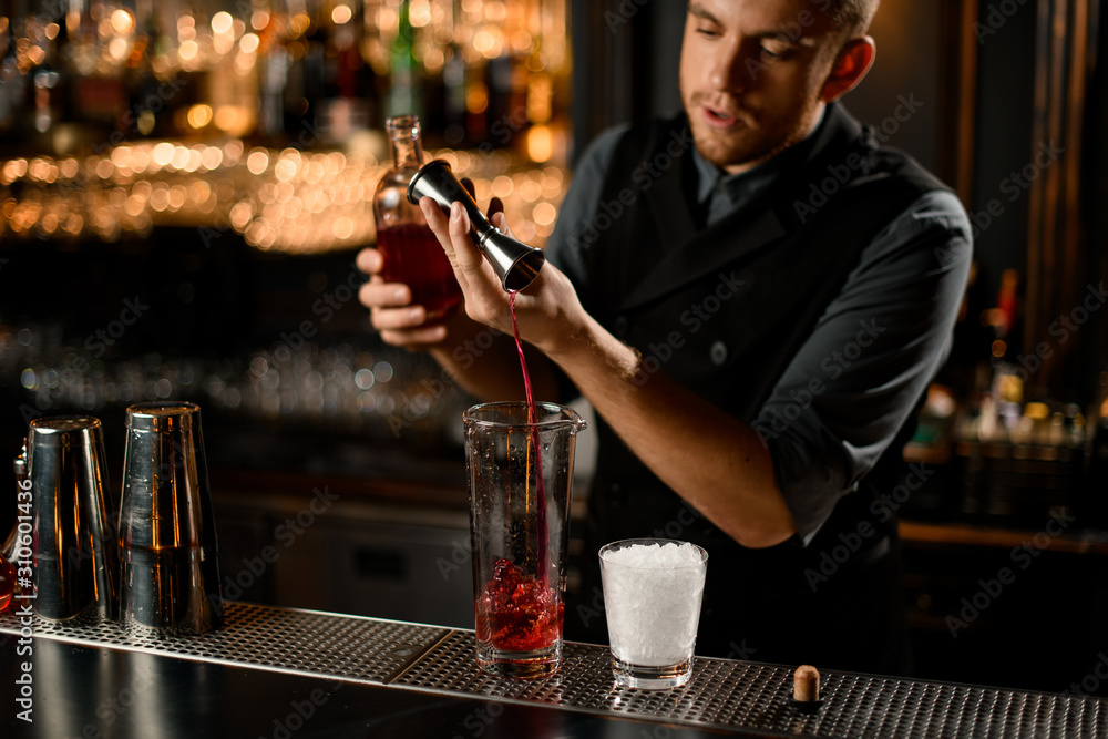 Bartender pouring liquor from jigger to glass