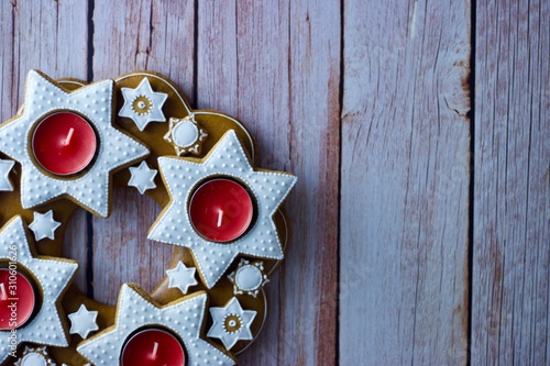 Christmas decorative advent wreath of gingerbread stars with candles on wooden background and copy space