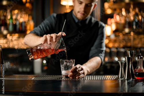 Close-up of bartender pouring cocktail from strainer