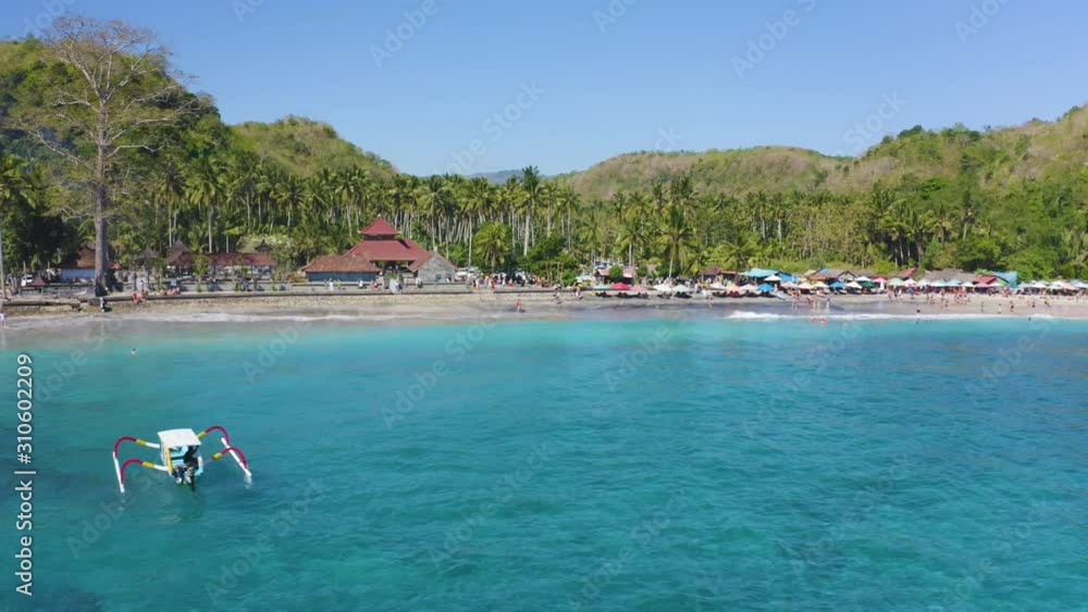 Slow fly over Crystal Bay Beach, Nusa Penida in Bali Indonesia. Traditional Balinese fishing boat with turquoise Ocean and White sand beach and tropical palm tree forest filmed in 4k Slow fly over Crystal Bay Beach, Nusa Penida in Bali Indonesia. Traditional Balinese fishing boat with turquoise Ocean and White sand beach and tropical palm tree forest filmed in 4k