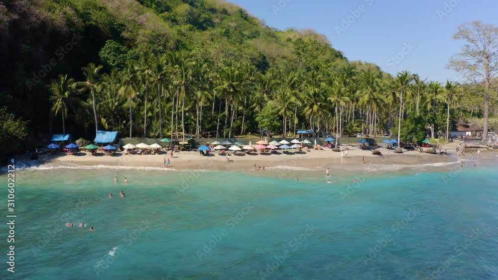 Crystal Bay Beach, Nusa Penida in Bali Indonesia cinematic drone footage flyover amazing tropical Hidden Beach with Volcano sand and Palm tree forest next to Indian Ocean in Blue clear color. Crystal Bay Beach, Nusa Penida in Bali Indonesia cinematic drone footage flyover amazing tropical Hidden Beach with Volcano sand and Palm tree forest next to Indian Ocean in Blue clear color.