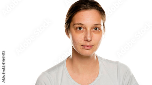 Portrait of young serious woman without makeup on white background