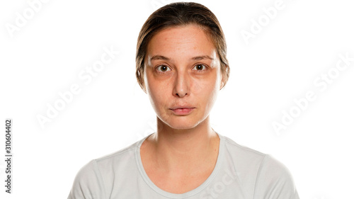 Portrait of young serious woman without makeup on white background