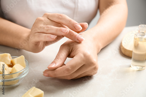 Woman applying organic cocoa butter at table, closeup