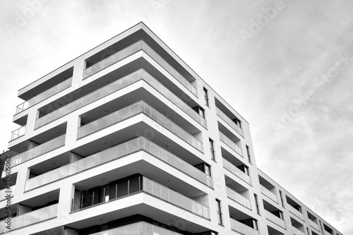 Sun rays light effects on urban buildings. Fragment of modern residential apartment with flat buildings exterior. Detail of new luxury house and home complex. Black and white.