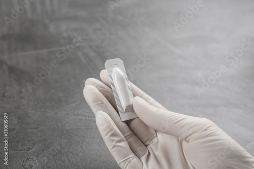 фотографія Woman holding suppository at grey table, closeup