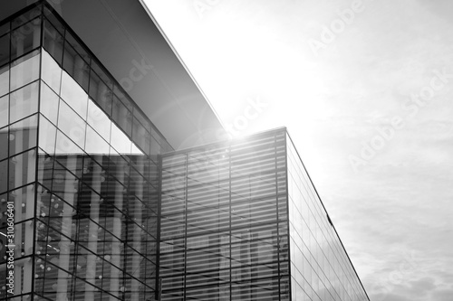 Sun rays light effects on urban buildings in sunset. Modern office building detail  glass surface with sunlight. Business background. Black and white.