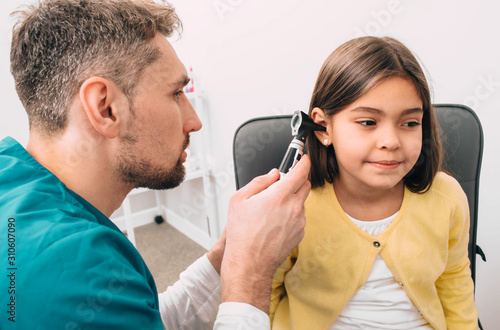 Ear exam. Pediatrician examining little mixed race child with otoscope, hearing exam of child
