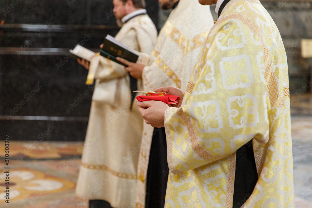 Naklejka premium The clergyman holds in his hands a cup of wine Cahors for the married bride and groom
