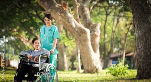 Asian senior woman sitting on the wheelchair  with woman in doctor uniform in the park hospital © chayathon2000